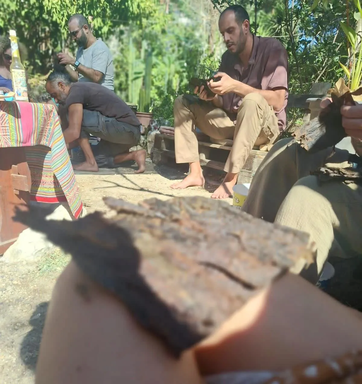 Participants sitting together in a traditional Rapeh preparation gathering, hand-processing Mapacho tobacco outdoors